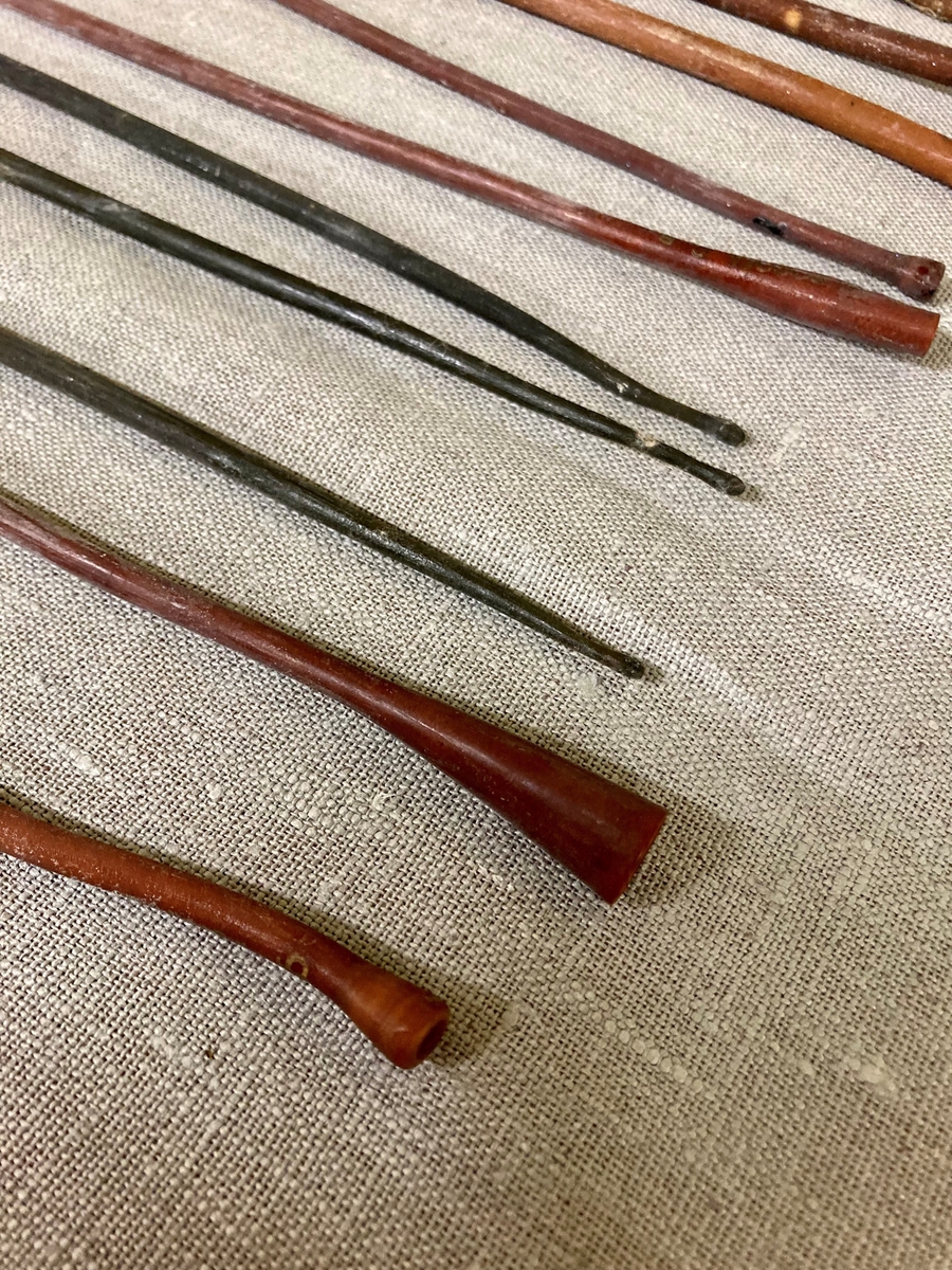 11 avlange pinneformede instrumenter i et gummilignende materiale. Bredere i den ene enden. Oppbevart i et glassrør.