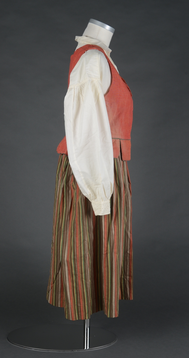 Tre-delt bunad:
A: Rødt liv med grønne kanter og hvitt bomulls fòr. Snittet er likt det som brukes til trønderbunaden. Skjøteliv med påsydd kappe og firkantete fliker i framkant. Det er sydd tittekant av grønt bomullstoff i livet og langs nedrekanten av skjøtet. Metallhekter til lukking.
B: Stakk av stripet bomullstoff i fargene brunt, rødt, gult, grønt og hvitt. Svakt rynket til linning. Lukkes med hekter og sekundært innsydd glidelås.
C: Stakk av samme snit og materiale som B. Linning med langsgående striper. Lukkes med hekter og tre trykknapper.
D: Skjorte i bomullstoff i primærsnitt. Påsydde skulderstykker, ståkrage og halssplitt med regels. Ermene er rynket til mansjetten. Mansjettene er brodert på grovere bomullstoff (sultan) med hardangersøm. Lukkes med metallhekter i messing.
Bunaden er i hovedsak maskinsydd. Som type er den trolig fra mellomkrigstida.