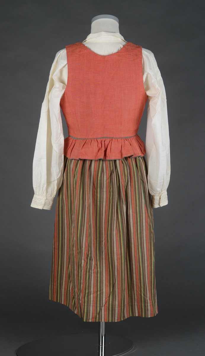 Tre-delt bunad:
A: Rødt liv med grønne kanter og hvitt bomulls fòr. Snittet er likt det som brukes til trønderbunaden. Skjøteliv med påsydd kappe og firkantete fliker i framkant. Det er sydd tittekant av grønt bomullstoff i livet og langs nedrekanten av skjøtet. Metallhekter til lukking.
B: Stakk av stripet bomullstoff i fargene brunt, rødt, gult, grønt og hvitt. Svakt rynket til linning. Lukkes med hekter og sekundært innsydd glidelås.
C: Stakk av samme snit og materiale som B. Linning med langsgående striper. Lukkes med hekter og tre trykknapper.
D: Skjorte i bomullstoff i primærsnitt. Påsydde skulderstykker, ståkrage og halssplitt med regels. Ermene er rynket til mansjetten. Mansjettene er brodert på grovere bomullstoff (sultan) med hardangersøm. Lukkes med metallhekter i messing.
Bunaden er i hovedsak maskinsydd. Som type er den trolig fra mellomkrigstida.