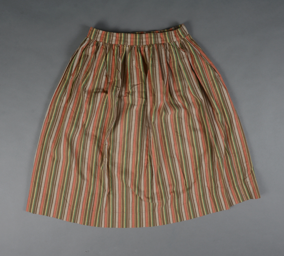 Tre-delt bunad:
A: Rødt liv med grønne kanter og hvitt bomulls fòr. Snittet er likt det som brukes til trønderbunaden. Skjøteliv med påsydd kappe og firkantete fliker i framkant. Det er sydd tittekant av grønt bomullstoff i livet og langs nedrekanten av skjøtet. Metallhekter til lukking.
B: Stakk av stripet bomullstoff i fargene brunt, rødt, gult, grønt og hvitt. Svakt rynket til linning. Lukkes med hekter og sekundært innsydd glidelås.
C: Stakk av samme snit og materiale som B. Linning med langsgående striper. Lukkes med hekter og tre trykknapper.
D: Skjorte i bomullstoff i primærsnitt. Påsydde skulderstykker, ståkrage og halssplitt med regels. Ermene er rynket til mansjetten. Mansjettene er brodert på grovere bomullstoff (sultan) med hardangersøm. Lukkes med metallhekter i messing.
Bunaden er i hovedsak maskinsydd. Som type er den trolig fra mellomkrigstida.