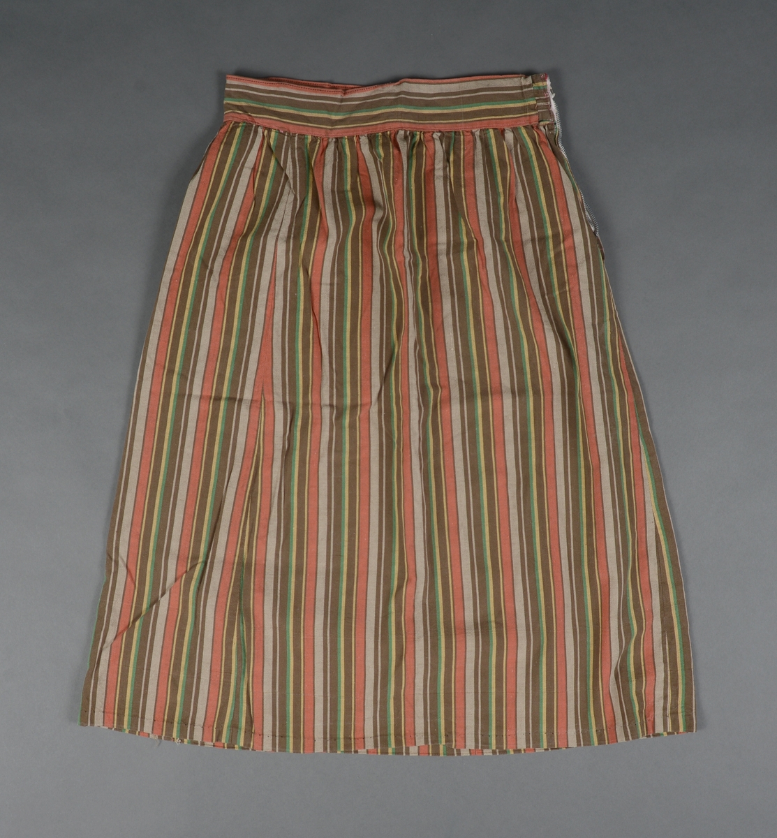 Tre-delt bunad:
A: Rødt liv med grønne kanter og hvitt bomulls fòr. Snittet er likt det som brukes til trønderbunaden. Skjøteliv med påsydd kappe og firkantete fliker i framkant. Det er sydd tittekant av grønt bomullstoff i livet og langs nedrekanten av skjøtet. Metallhekter til lukking.
B: Stakk av stripet bomullstoff i fargene brunt, rødt, gult, grønt og hvitt. Svakt rynket til linning. Lukkes med hekter og sekundært innsydd glidelås.
C: Stakk av samme snit og materiale som B. Linning med langsgående striper. Lukkes med hekter og tre trykknapper.
D: Skjorte i bomullstoff i primærsnitt. Påsydde skulderstykker, ståkrage og halssplitt med regels. Ermene er rynket til mansjetten. Mansjettene er brodert på grovere bomullstoff (sultan) med hardangersøm. Lukkes med metallhekter i messing.
Bunaden er i hovedsak maskinsydd. Som type er den trolig fra mellomkrigstida.