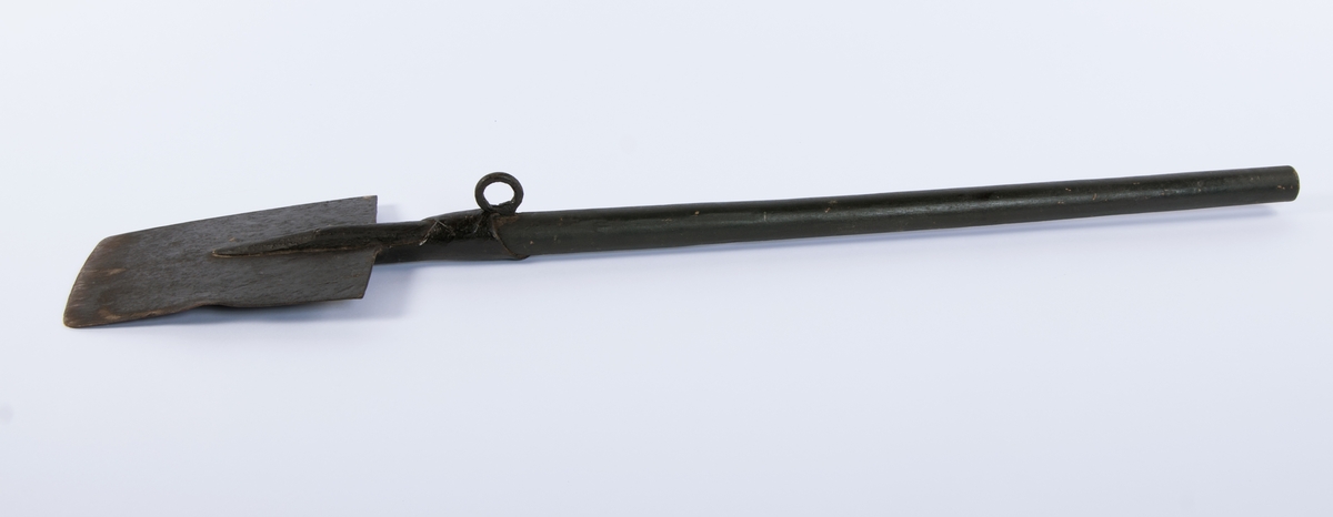 Langt, rett skaft stukket gjennom falen, ender i et spor på spadens iunderside. rett, trapesformet blad. Kraftig krok på skaftets underside, ved falen.
3 uidentifiserte stempler på bladets overside, mulig en kronet C (?)