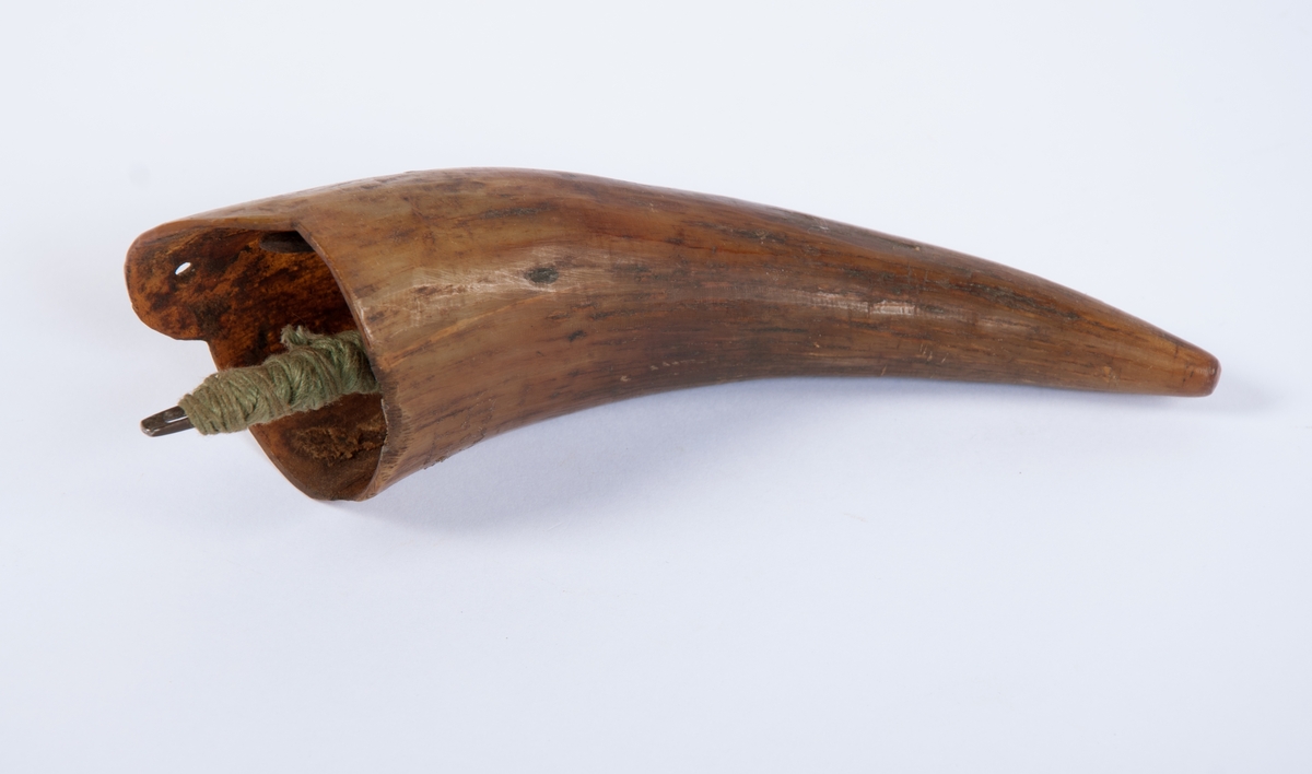 Nålehorn laget av kuhorn. Hempe og 2 hull for oppheng. Fylt med en blanding av bivoks og tjære. Inneholder 5 seilnåler.