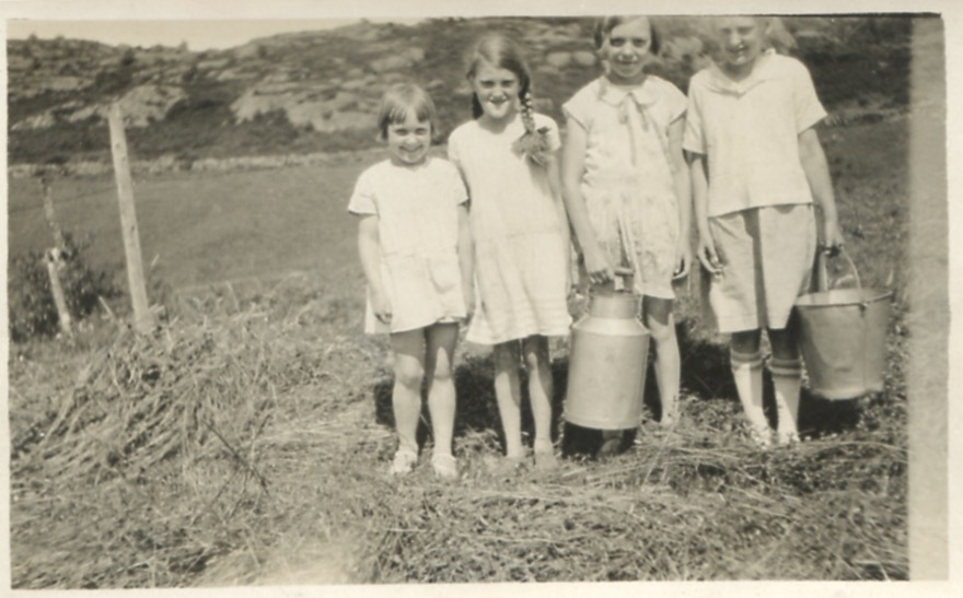 Fyra barn står på en äng, Långåker 1:3 "Natanaels" (senare hembygdsgården), okänt årtal. Ett av barnen håller en mjölkkanna ett annat barn håller en plåthink.
Från vänster: 1. Britt Smitt Petersson (född 1922). 2. sommargäst Rut Lind (född 1918). 3. Nina Bengtsson (född 1918, gift Nilsson). 4. Okänd.
Nr 1 och 3 är kusiner.