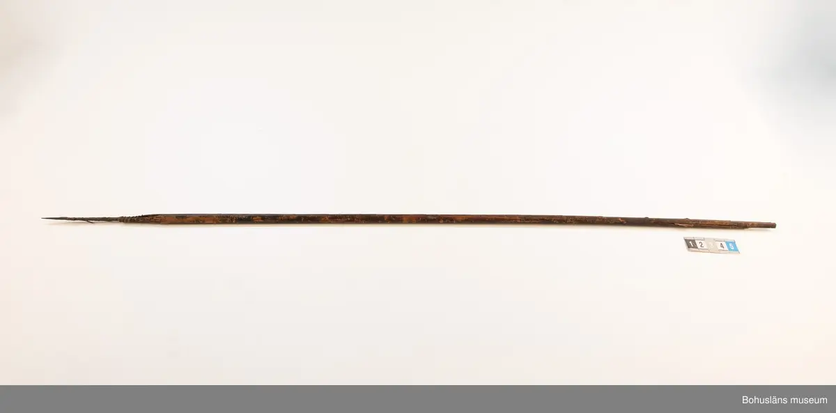 Ur handskrivna katalogen 1957-1958:
Båge m. 17 pilar, Afrika
Bågen a) L.103 cm; m. sträng av en vidja; i bågens ändar runda träkulor. Hel.
b-l, 3- kantiga m. smal svart fastsurrad träspets m. hullingar.
b-c, L. 72 och 71,2 cm; har blad infällda i ändan som styrfjädrar. Bladen saknas vid inventering 2022.
d-k, L. 75,5; 72; 71,8; 71,8; 71,6; 71,5; 76,6; 66 cm; lika b och c men saknar styrfjädrar;
k upptrasad i ändan.
l, L. 55,5; av ngt annan typ än föreg, har haft spets och styrfjädrar, vila saknas.
m-r, runda skaft, styrfjädrar, spetsen av järn m. hullingar (ej 791 m) och holk f. fastsättn.
L. 69; 68,1; 76,4; 65; 64,7; 61,3 cm;
("r" saknar spets; n och q saknar en hulling. "o" saknar 2 styrfjädrar; "p" saknar ena delen i "klykan" f. strängen)

Ur Knut Adrian Anderssons Katalog II 1916:
No 22, nr 7, 8 ,9 på etiketten i Elmer Göranssons samling. Båge av trä m. sena till sträng jämte 17 förgiftade pilar av två typer med hullingar. Från Mogala i Belgiska Congo.

Artikel i Bohusläningen måndagen den 1 november 1937, "Vittberesta bohusläningar berätta. Upplevelser under 30-årig vistelse i Belgiska Kongo. Kapen Elmer Göransson. Folk och sedvänjor under ekvatorns glödande sol."

UMFA54467:0588 visar porträtt på sjökapten Elmer Göransson i uniform med ett antal ordnar och utmärkelser. Fotograf Thure Nihlén, Uddevalla.