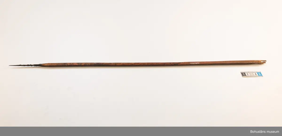 K: Sprucken i bakre änden.

Ur handskrivna katalogen 1957-1958:
Båge m. 17 pilar, Afrika
Bågen a) L.103 cm; m. sträng av en vidja; i bågens ändar runda träkulor. Hel.
b-l, 3- kantiga m. smal svart fastsurrad träspets m. hullingar.
b-c, L. 72 och 71,2 cm; har blad infällda i ändan som styrfjädrar.
d-k, L. 75,5; 72; 71,8; 71,8; 71,6; 71,5; 76,6; 66 cm; lika b och c men saknar styrfjädrar;
k upptrasad i ändan.
l, L. 55,5; av ngt annan typ än föreg, har haft spets och styrfjädrar, vila saknas.
m-r, runda skaft, styrfjädrar, spetsen av järn m. hullingar (ej 791 m) och holk f. fastsättn.
L. 69; 68,1; 76,4; 65; 64,7; 61,3 cm;
("r" saknar spets; n och q saknar en hulling. "o" saknar 2 styrfjädrar; "p" saknar ena delen i "klykan" f. strängen)

Ur Knut Adrian Anderssons Katalog II 1916:
No 22, nr 7, 8 ,9 på etiketten i Elmer Göranssons samling. Båge av trä m. sena till sträng jämte 17 förgiftade pilar av två typer med hullingar. Från Mogala i Belgiska Congo.

Artikel i Bohusläningen måndagen den 1 november 1937, "Vittberesta bohusläningar berätta. Upplevelser under 30-årig vistelse i Belgiska Kongo. Kapen Elmer Göransson. Folk och sedvänjor under ekvatorns glödande sol."

UMFA54467:0588 visar porträtt på sjökapten Elmer Göransson i uniform med ett antal ordnar och utmärkelser. Fotograf Thure Nihlén, Uddevalla.
