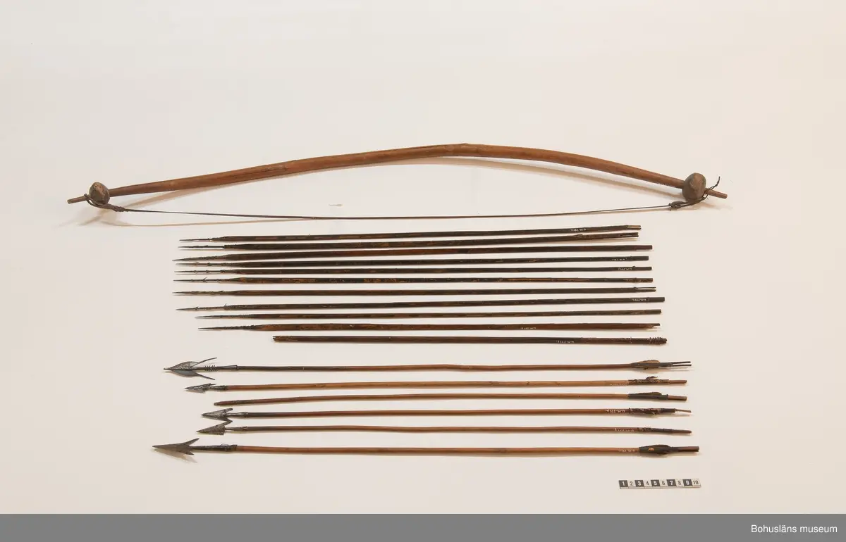 Ur handskrivna katalogen 1957-1958:
Båge m. 17 pilar, Afrika
Bågen a) L.103 cm; m. sträng av en vidja; i bågens ändar runda träkulor. Hel.
b-l, 3- kantiga m. smal svart fastsurrad träspets m. hullingar.
b-c, L. 72 och 71,2 cm; har blad infällda i ändan som styrfjädrar.
d-k, L. 75,5; 72; 71,8; 71,8; 71,6; 71,5; 76,6; 66 cm; lika b och c men saknar styrfjädrar;
k upptrasad i ändan.
l, L. 55,5; av ngt annan typ än föreg, har haft spets och styrfjädrar, vila saknas.
m-r, runda skaft, styrfjädrar, spetsen av järn m. hullingar (ej 791 m) och holk f. fastsättn.
P: Fragmenterade styrfjädrar och en lös styrfjäder.
L. 69; 68,1; 76,4; 65; 64,7; 61,3 cm;
("r" saknar spets; n och q saknar en hulling. "o" saknar 2 styrfjädrar; "p" saknar ena delen i "klykan" f. strängen)

Ur Knut Adrian Anderssons Katalog II 1916:
No 22, nr 7, 8 ,9 på etiketten i Elmer Göranssons samling. Båge av trä m. sena till sträng jämte 17 förgiftade pilar av två typer med hullingar. Från Mogala i Belgiska Congo.

Artikel i Bohusläningen måndagen den 1 november 1937, "Vittberesta bohusläningar berätta. Upplevelser under 30-årig vistelse i Belgiska Kongo. Kapen Elmer Göransson. Folk och sedvänjor under ekvatorns glödande sol."

UMFA54467:0588 visar porträtt på sjökapten Elmer Göransson i uniform med ett antal ordnar och utmärkelser. Fotograf Thure Nihlén, Uddevalla.