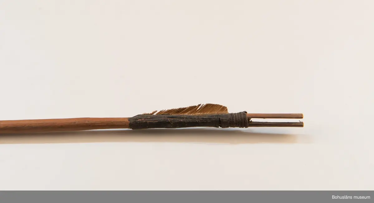 Ur handskrivna katalogen 1957-1958:
Båge m. 17 pilar, Afrika
Bågen a) L.103 cm; m. sträng av en vidja; i bågens ändar runda träkulor. Hel.
b-l, 3- kantiga m. smal svart fastsurrad träspets m. hullingar.
b-c, L. 72 och 71,2 cm; har blad infällda i ändan som styrfjädrar.
d-k, L. 75,5; 72; 71,8; 71,8; 71,6; 71,5; 76,6; 66 cm; lika b och c men saknar styrfjädrar;
k upptrasad i ändan.
l, L. 55,5; av ngt annan typ än föreg, har haft spets och styrfjädrar, vila saknas.
m-r, runda skaft, styrfjädrar, spetsen av järn m. hullingar (ej 791 m) och holk f. fastsättn.
L. 69; 68,1; 76,4; 65; 64,7; 61,3 cm;
("r" saknar spets; n och q saknar en hulling. "o" saknar 2 styrfjädrar; "p" saknar ena delen i "klykan" f. strängen)
O: Saknar pilspets vid inventering 2022. Endast en styrfjäder kvar.

Ur Knut Adrian Anderssons Katalog II 1916:
No 22, nr 7, 8 ,9 på etiketten i Elmer Göranssons samling. Båge av trä m. sena till sträng jämte 17 förgiftade pilar av två typer med hullingar. Från Mogala i Belgiska Congo.

Artikel i Bohusläningen måndagen den 1 november 1937, "Vittberesta bohusläningar berätta. Upplevelser under 30-årig vistelse i Belgiska Kongo. Kapen Elmer Göransson. Folk och sedvänjor under ekvatorns glödande sol."

UMFA54467:0588 visar porträtt på sjökapten Elmer Göransson i uniform med ett antal ordnar och utmärkelser. Fotograf Thure Nihlén, Uddevalla.