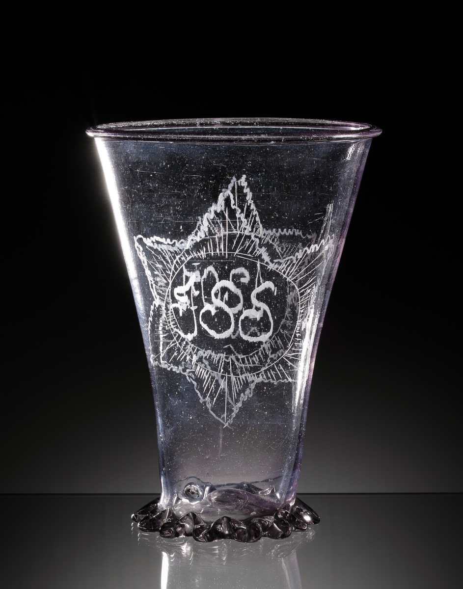 Bägare, s.k. "silverform".
Beskrivning: Pålagt, knipt glasband som bildar en fot. Graverad stjärna 
med initialerna "I.I.S." och ytterligare en stjärna med årtalet "1807".
Färg: Gråviolett klarglas.
Mått: Ovan angivna mått avser höjd och bredd upptill.
Inskrivet i huvudkatalogen 1937.