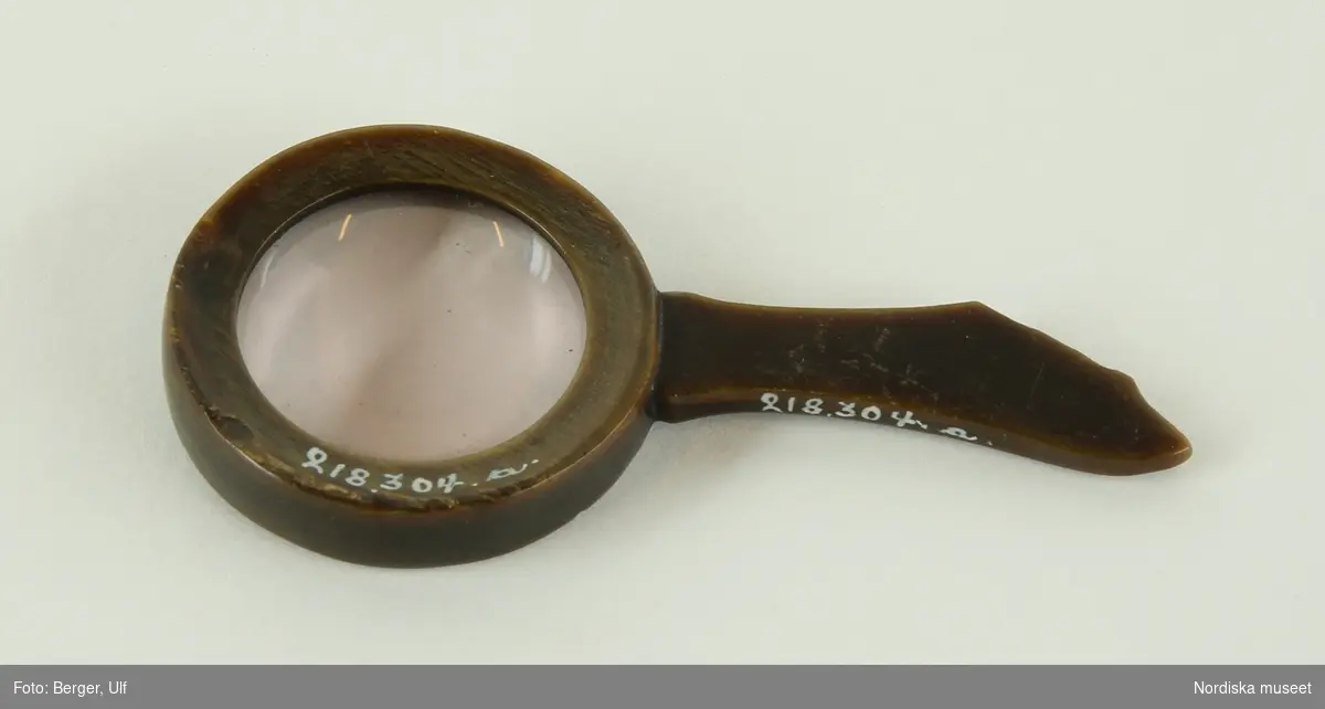 Huvudliggaren:
"a-b Förstoringsglas, runt, ram av horn, handtag av horn; i yngre etui; ljusbrunt skinn med Linnea, fällock; sign. 'F Beck & son Stockholm'; med guldtryck i locket: 'Carl v. Linnés förstoringsglas skänkt af hans dotter till Dr Claes Grill'. G[åva] 23/5 1939 av överstinnan Maria Grill, f. Reuterskiöld, Stockholm."