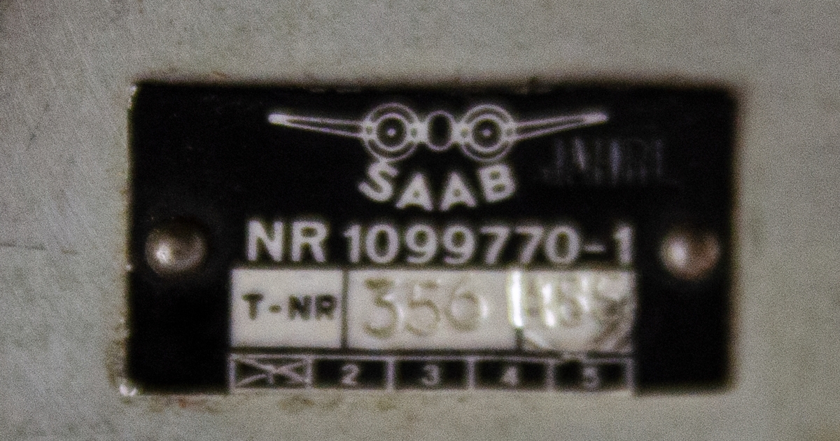 Spakservo, tillhörandes flygplan 32, Lansen. Av metall, oregelbunden form med flera utskjutande delar. Uppskuren för undervisning och monterad på stativ. Tillverkad av SAAB, nummer: 1102355-1.