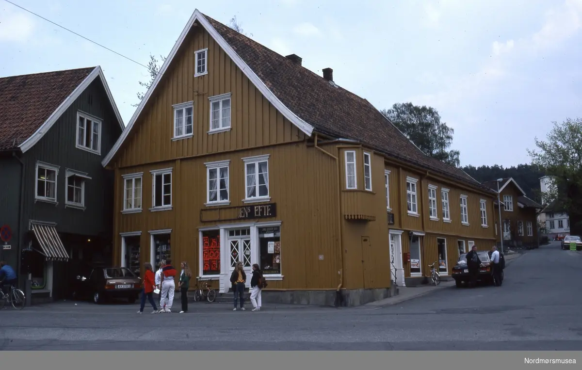 Foto trolig fra et gateparti i Drøbak i Frogn kommune i Viken fylke. Datering er trolig på 1980-tallet. Fra Stein Magne Bach sin private fotosamling. Denne samlingen består av dias fra perioden omkring 1980. Fra Nordmøre museums fotosamlinger.