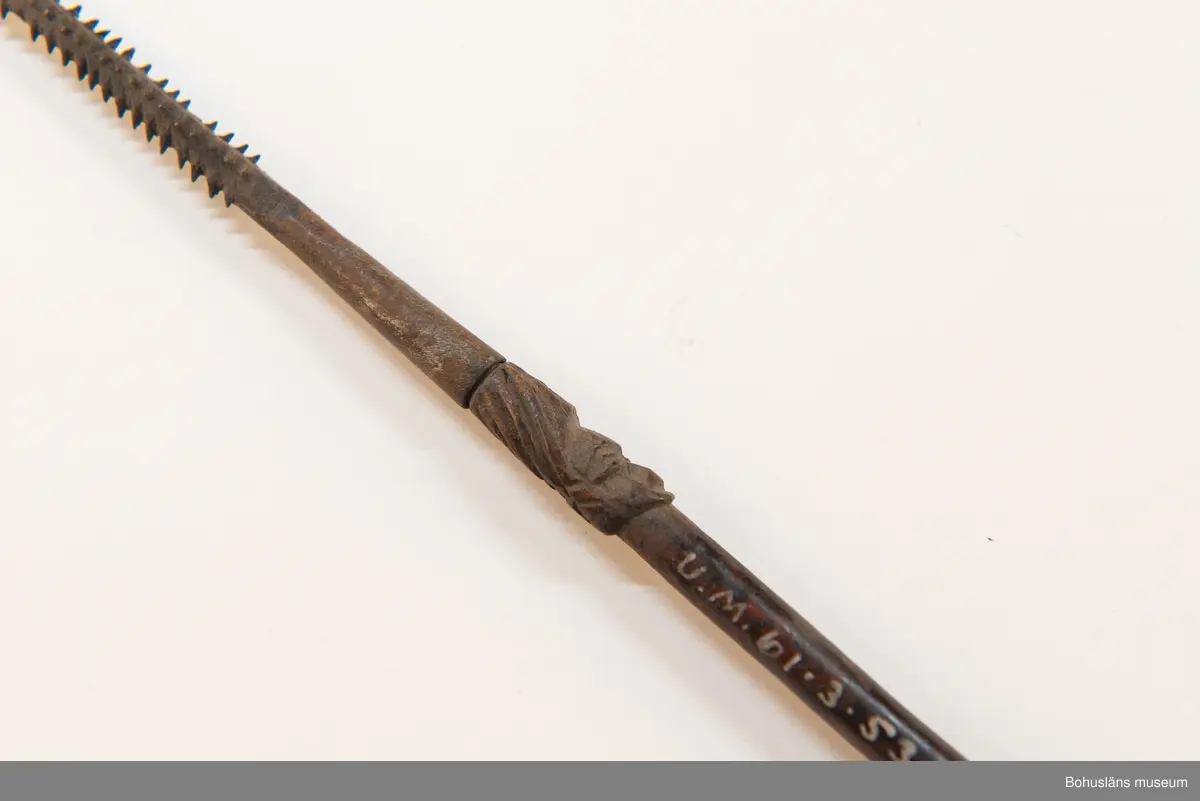 Kontinent: Afrika.

Ur lappkatalogen:
Pil, l. 94 cm. Spets av järn med två stora hullingar o. en mängd smärre. Skaftholk på sticka, instucken i skaftet o. surrad. Stickan försedd med skurna ornament o. två människoansikten i relief. 10 styrfjädrar, något vridna. Mangbetu el. Azande.

Uppgifter om E. Göransson i Knut Adrian Anderssons katalog samt historik om samlingen: Se UM61.3.1