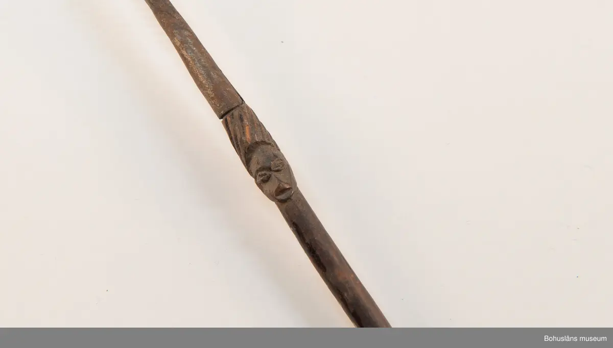 Kontinent: Afrika.

Ur lappkatalogen:
Pil, l. 94 cm. Spets av järn med två stora hullingar o. en mängd smärre. Skaftholk på sticka, instucken i skaftet o. surrad. Stickan försedd med skurna ornament o. två människoansikten i relief. 10 styrfjädrar, något vridna. Mangbetu el. Azande.

Uppgifter om E. Göransson i Knut Adrian Anderssons katalog samt historik om samlingen: Se UM61.3.1