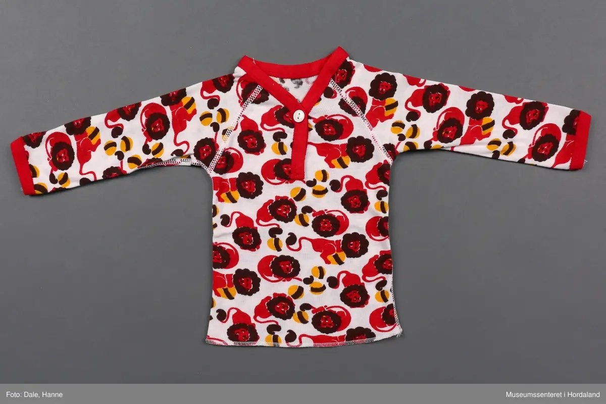 Plagget: Løver med ball i brunt, rødt og gult.
Emballasjen: Fargefoto av baby.