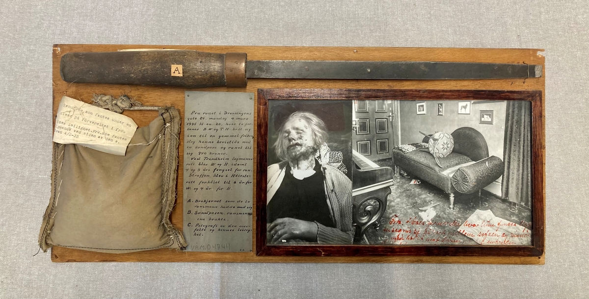 Bevisgjenstander, tekstplansjer og foto montert på en rektangulær treplate.