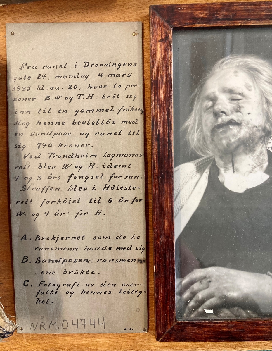 Bevisgjenstander, tekstplansjer og foto montert på en rektangulær treplate.