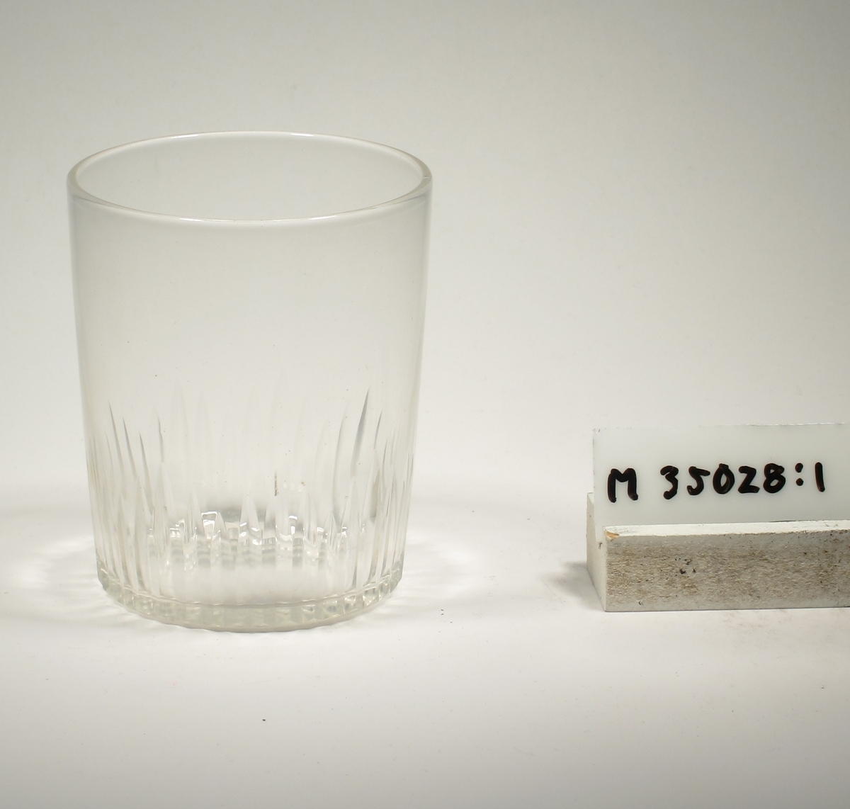 Svagt konande med skärslipade, stående linjer i olika höjder på nedre delen.