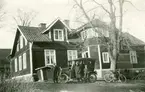 Exteriör av bostadshuset Solhem vid Malmen, omkring 1930-1940. En familj står framför en bil utanför huset.