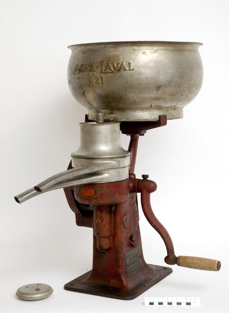 Separator Alfa-Laval 21 bestående av a) växelhus med vev och stativ b) mjölkbehållare, c-d) urtappningsanordning för mjölk och smörfett. 

a) växelhuset står på en rektangulär platta med hål för fyra fästeskruvar. Plattan övergår i en sockel med ovalt tvärsnitt i vars överdel infattats växelhus med kantkuggat hjul drivet av en handvev på motsatta sidan. Sockeln avslutats upptill i ett trearmat stativ. Samtliga delar av gjutjärn, rödlackerade. Tillverkarskylten av svart lackerad mässing placerad på sockelns nedre del under vevfästet. 

b) mjölkbehållaren 35 cm i diameter, höjd 18,9 cm. Den övre kanten något inåtböjd. Firmanamnet Alfa-Laval 21 i relief med 2 cm höga bokstäver. Under texten en avtappningskran med utsläppet i behållarens botten, placerat något på ena sidan. 

c) urtappningsanordning för mjölk består av en cylindrisk behållare 13,5 cm i diameter med spillrör 16,7 cm långt samt en flottör inne i cylidnern. 

d) urtappniningsanordning för grädde (mjölkfett) försedd med spillrör såsom föregående. En rund samlare med en tratt i mitten. Tratthållet 4,5 cm i diameter. 