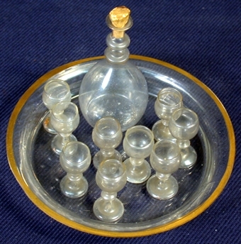 :1 Cirkelrund bricka av glas med hög kant med guldfärgad bård runt hela kanten. Diameter 90 mm, höjd: 15 mm.
   :2 Karaff av glas, oval form, smalnande hals med täljd kork i öppningen. Höjd: 62 mm, diameter i botten: 22 mm.
   :3-11 Nio stycken likadana dryckesglas på hög fot av glas. Höjd: 23 mm, diameter i öppning: 10 mm.
