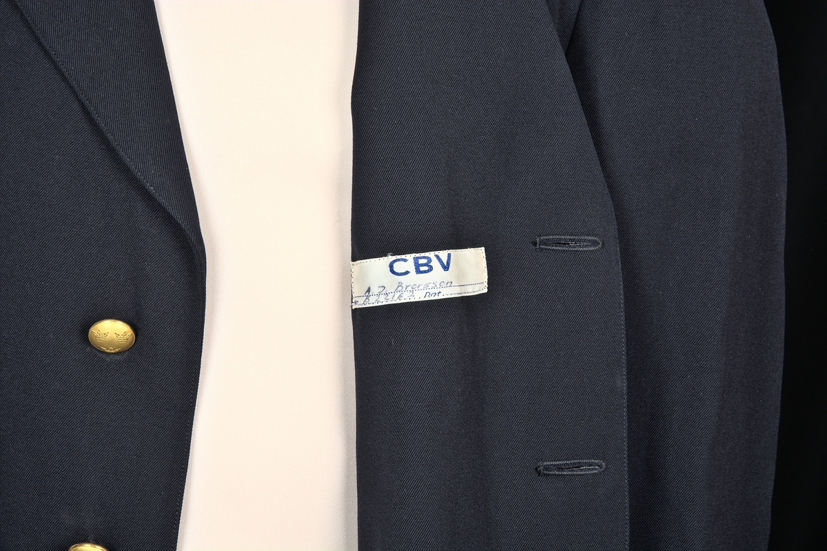Enkelknäppt uniformskavaj av marinblått tyg. Försedd med 3 gulmetallknappar dekorerade med vapensköld (tre kronor). Två fickor längs sidorna samt en bröstficka. Fodrad med grått satintyg i ärmar. På kavajens insida (vid vänstra bröstet) sitter en märkt etikett: "CBV" - "A.J. Brorsson. Nr B2212. DAT."