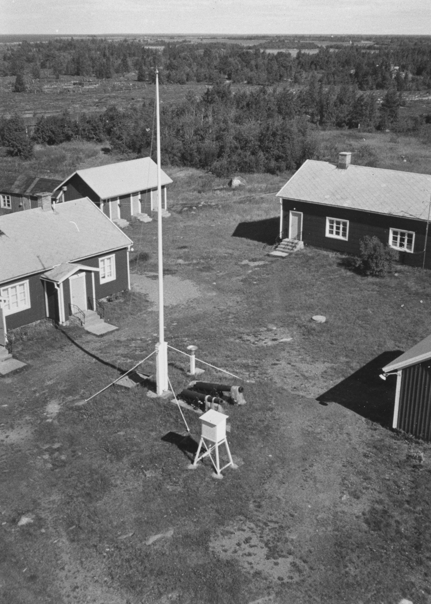 Holmögadds fyrplats sedd från fyrtornet. Mellan de båda bostadshusen syns en förrådsbyggnad.