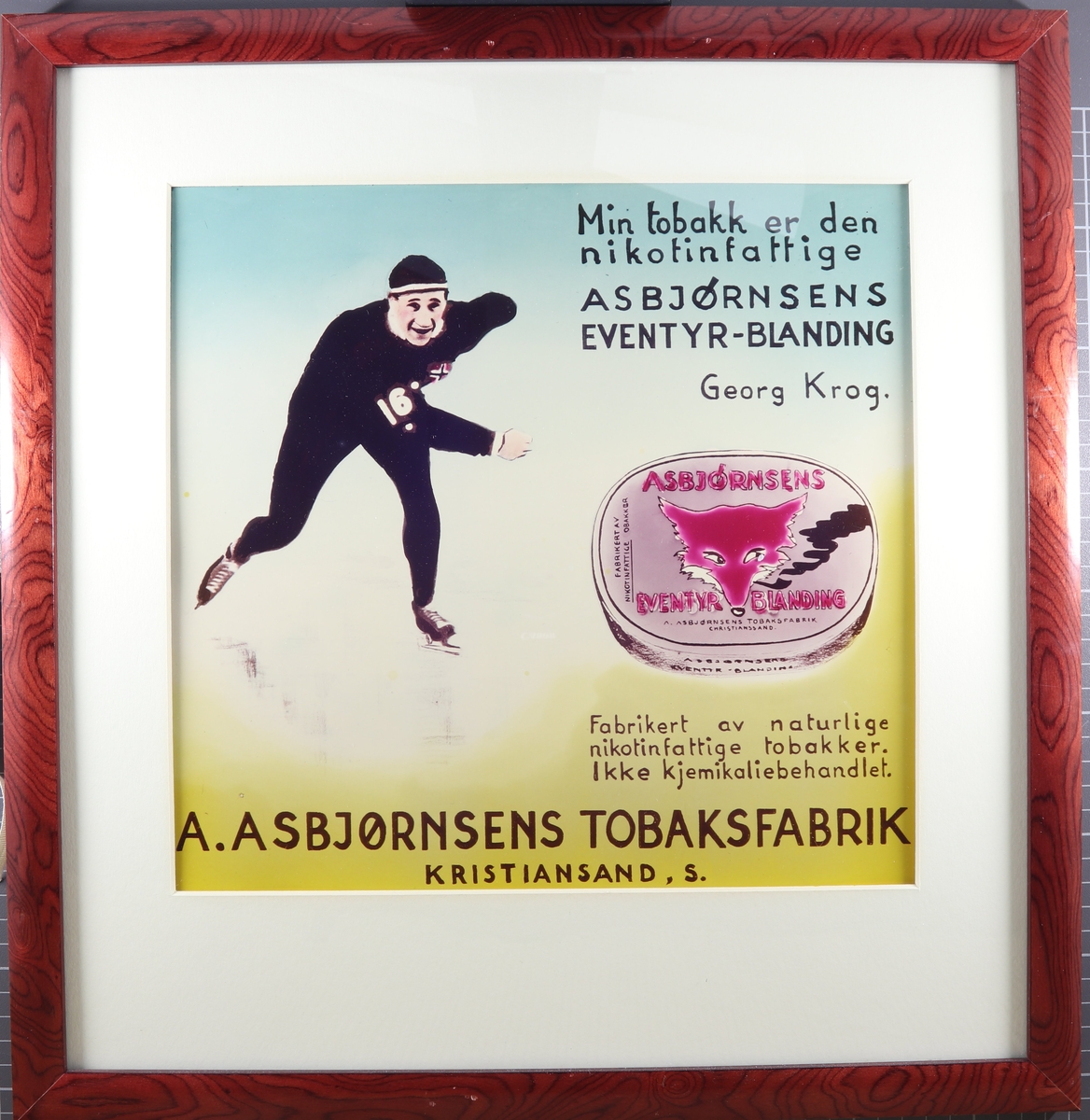 Skøyteløper ved siden av en boks eventyrblanding. Over står teksten "Min tobakk er den nikotinfattige Asbjørnsens Eventyrblanding Georg Krog" Under står teksten "Fabrikert av naturlige nikotinfattige tobakker. Ikke kjemikaliebehandlet."