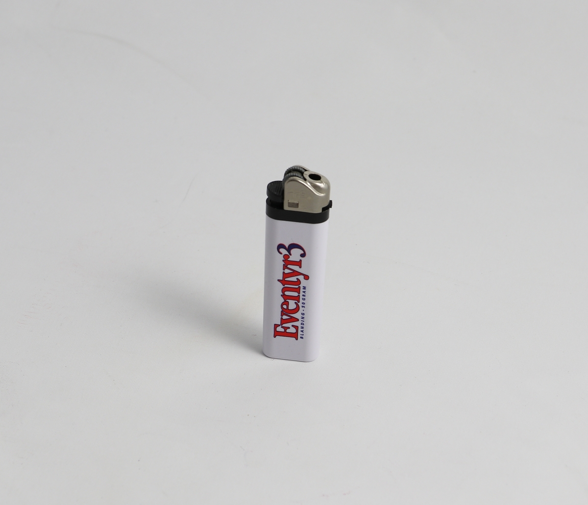 Hvit plast tank med revelogo og skriften "Asbjørnsen" på den ene siden, skriften "Eventyr 3" på andre siden. Tennmekanisme på toppen bestående av metall og svartplast.