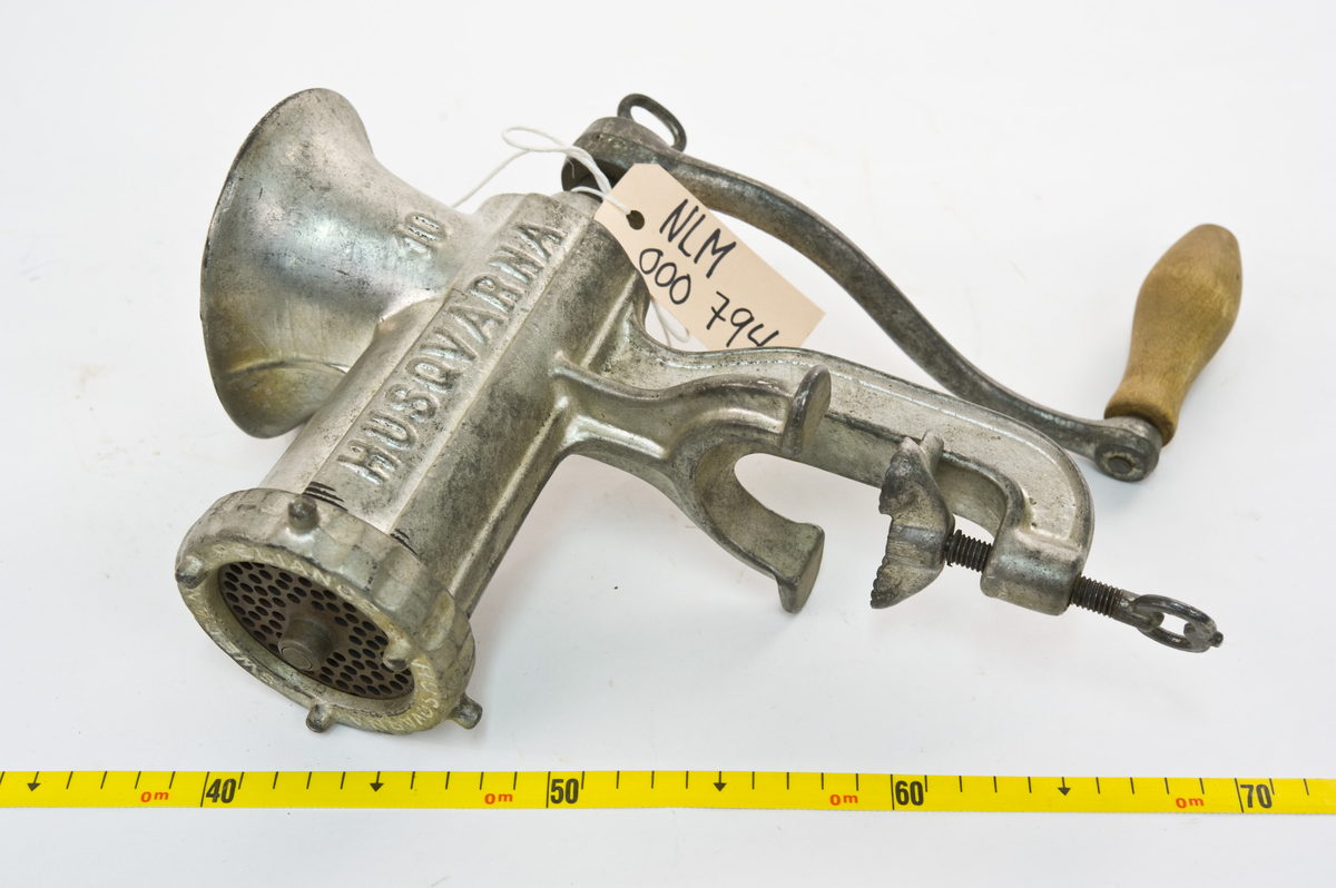 Støpt metallkvern med bordfeste for maling av kjøtt ag annen råvare. Håndrevet- avtakbar sveiv med trehåndtak.Inneholder en sylindrisk kvern med en spiralformet metallkniv og en perforert rund skive i front hvor det kvernete kjøttet kommer ut. Fronten kan skrus av for andre innsatser.