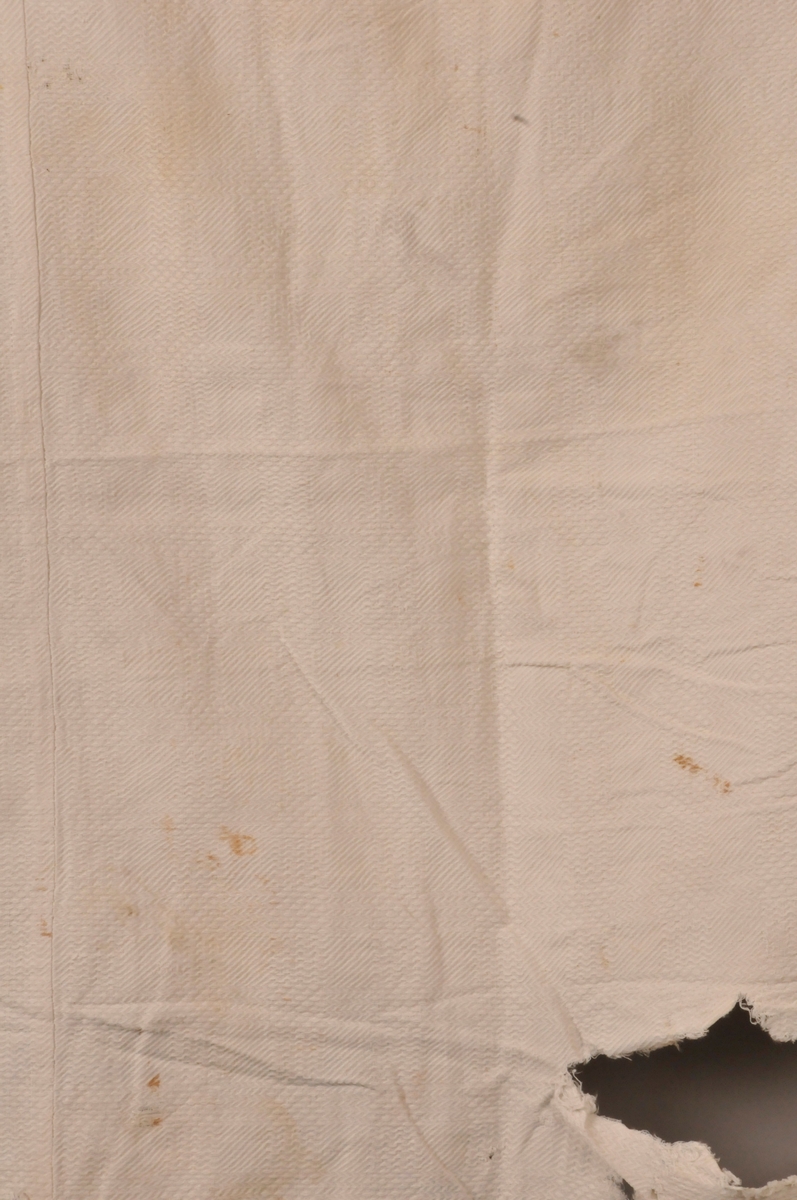 Duk i bomull med rutemønster i vevinga. Kant i same stoff som resten av duken. Rektangulær. Maskinsydd duk. Bøtt nokre satder. Restar av blonde kring tre av sidene.