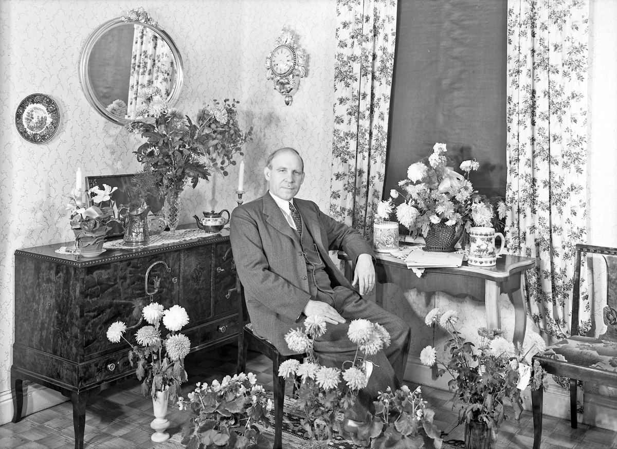Okänd man fotograferad tillsammans med blommor på sin födelsedag. 