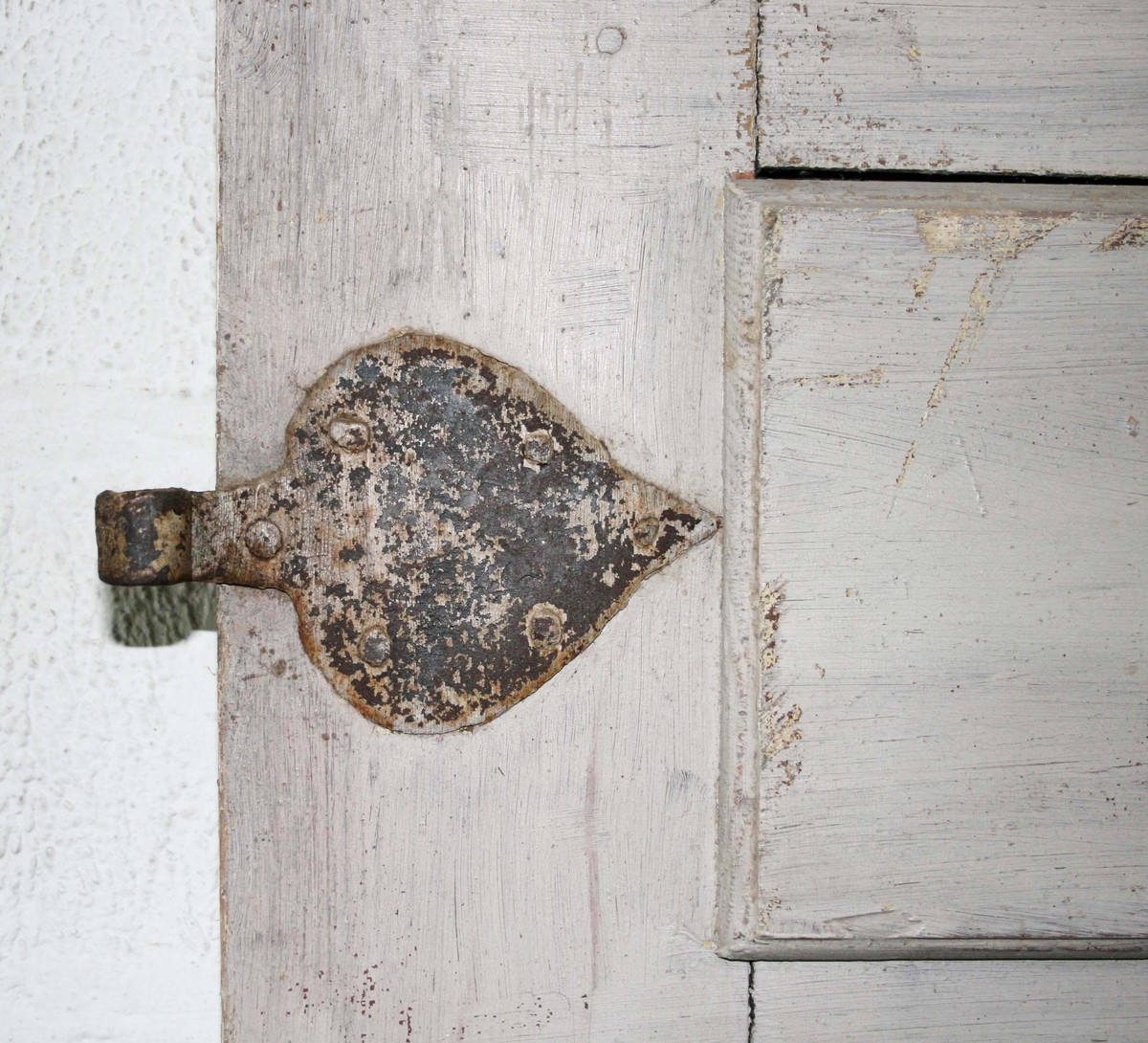 Dörr med 4 speglar, 2 liggande, 2 stående. Ena sidan grå, andra sidan vit. 2 stora lövformade beslag. Lås. Bruks-och färgslitage.

Till dörren hör foder.