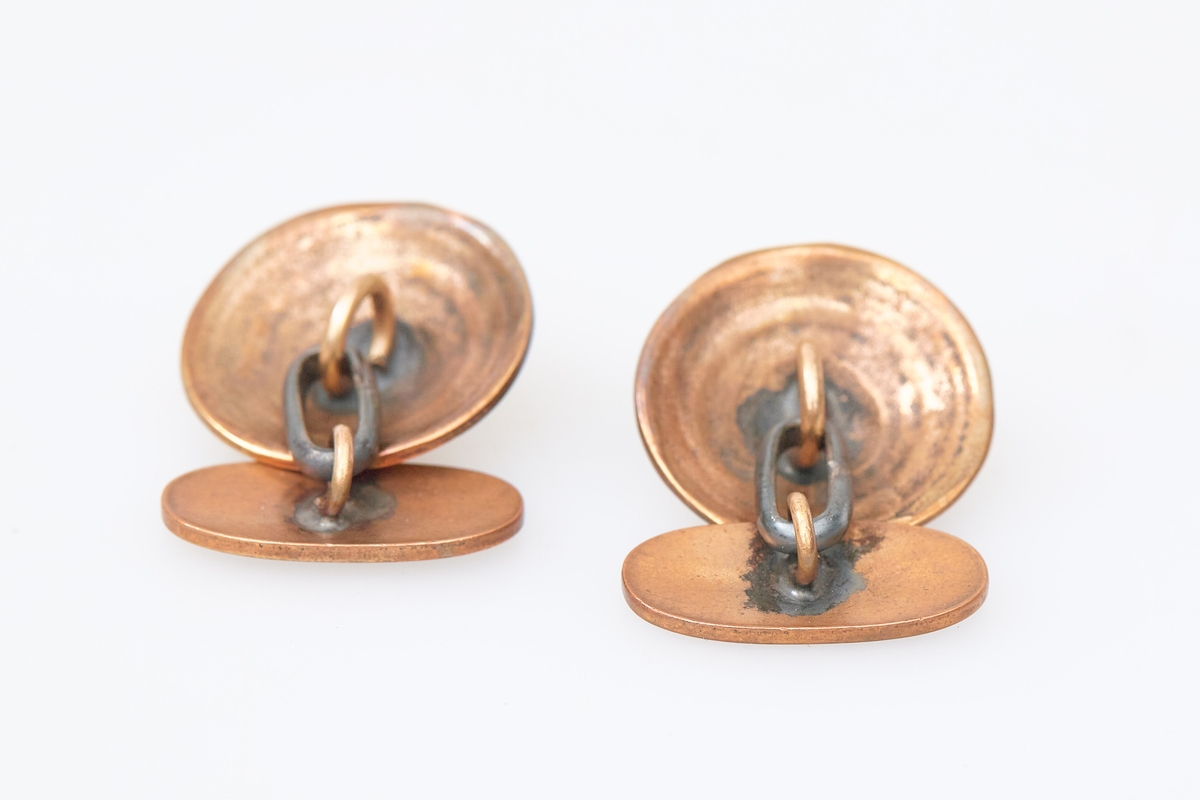 Et par mansjettknapper i bronse med dekor som etterligner totennåla. Brukt med totendrakt.