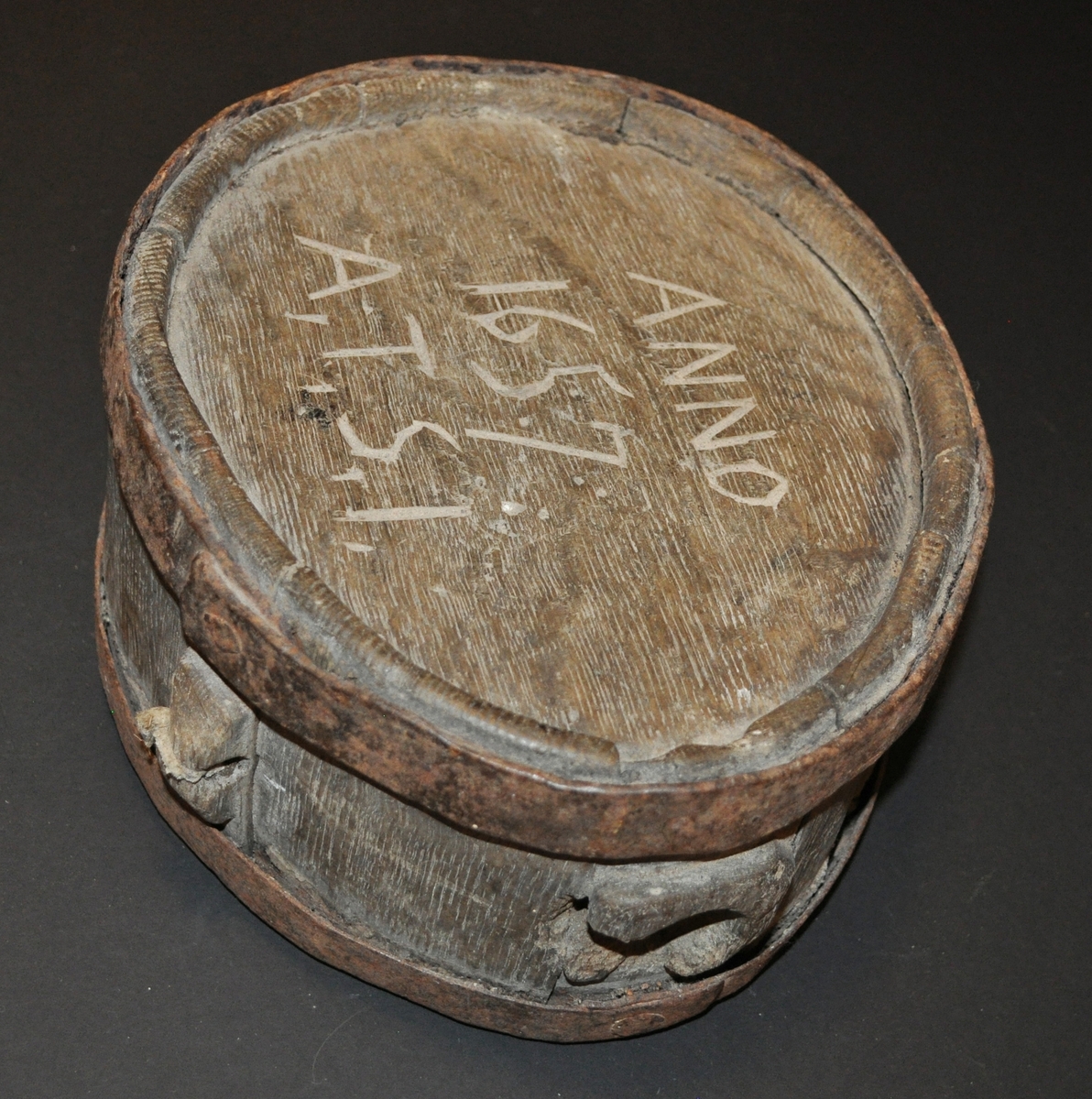 En kagge tillverkad i laggteknik med två laggband av järn. Oval form som är avsmalnad på ena sidan. Kaggen har ett tapphål. Text karvad på ovanlocket. Det finns spår efter handtag på sidan av kaggen.