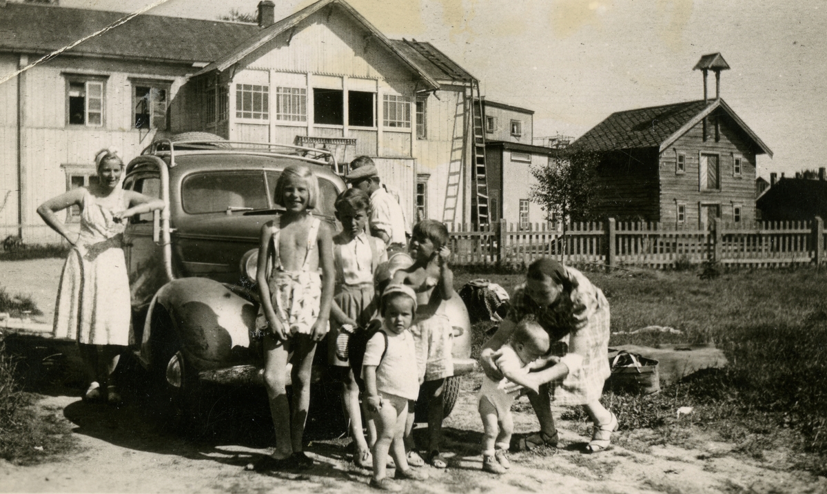 Voksne og barn foran bil