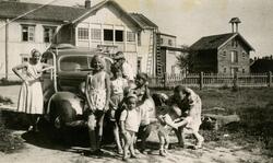 Voksne og barn foran bil