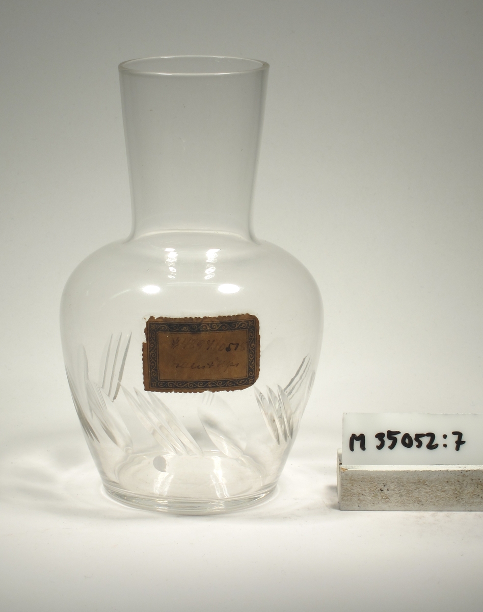 Ovoid med utvikt hals/mynning. Snedställda oliver och skär.

Karaffen samhör med vattenglaset M 35052:8