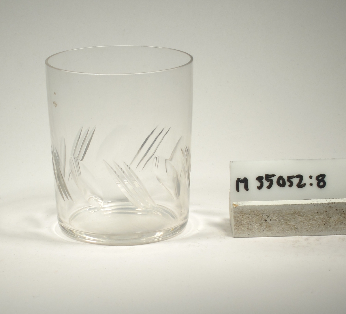 Cylinderformad. Snedställda oliver och skär.
Samhör med M 35052:7