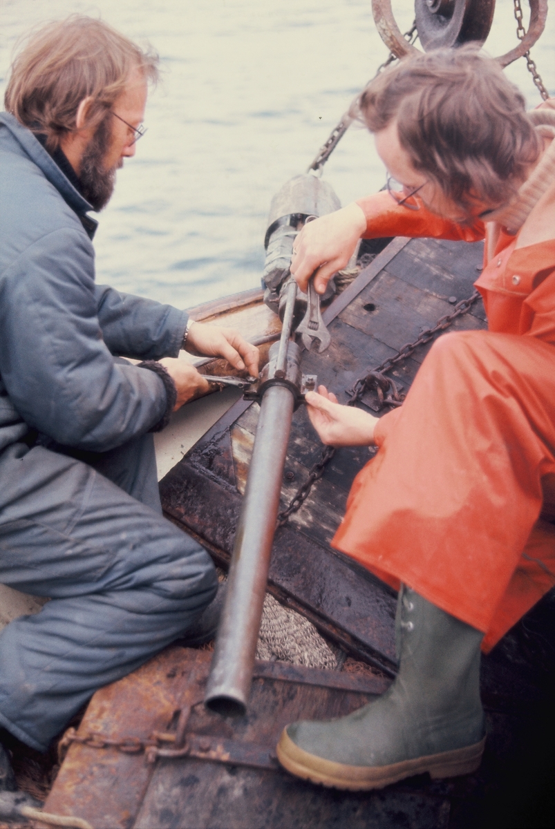 To menn arbeider med et stålrør på dekk på ei treskute, antageligvis "MS Gulafjord".