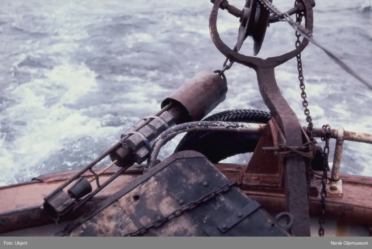 Et instrument for prøvetaking er festet til en kjetting i baugen på ei treskute, antageligvis "MS Guldfjord".