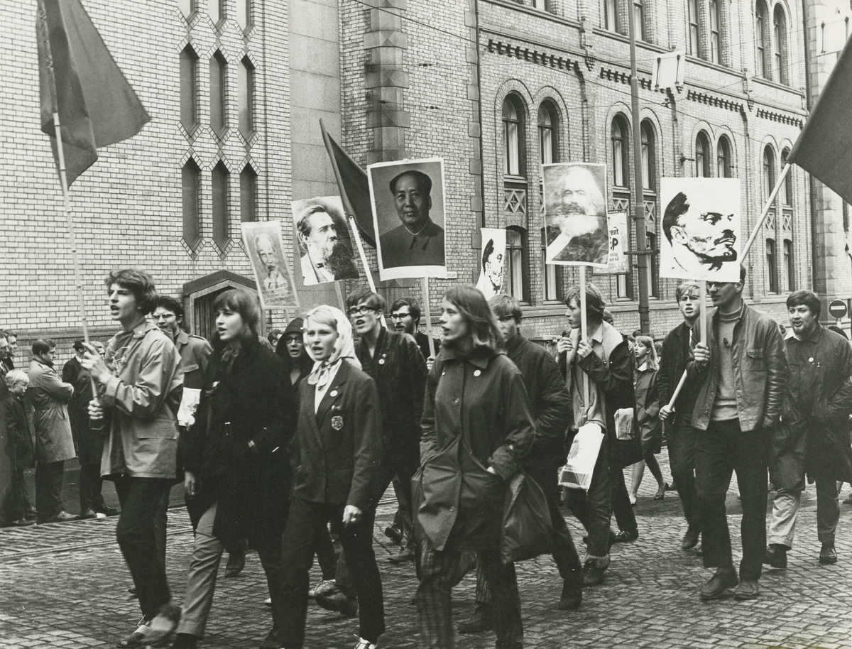 Ungdom i et demonstrasjonstog uten for Stortinget 1. mai 1968. De holder plakater med bilder av kjente kommuniser og flagg.  Utstillingstekst¤ Paul A. Røstad (1908-86) vokste opp på Ranheim utenfor Trondheim, og flyttet senere til Oslo der han fikk kontorjobb i et maskinfirma på 1930-tallet. Etter å ha dyrket fotografering som hobby gjennom en årrekke, sa han opp sin stilling og etablerte seg som profesjonell fotograf tidlig på 1950-tallet. Røstad la stor vekt på uavhengighet og drev livet gjennom et enmannsforetak fra sin bopel på Grefsen. Han tok bilder over hele Norge og var særlig opptatt av natur- og kulturlandskaper. Bilder fra gårdsdrift og husdyrholdgår igjen, ved siden av arkitekturfotografering. På 1960-tallet orienterte Røstad seg også mot nyhets- og reportasjefotografering, og leverte bilder blant annet til A-Magasinet. Bildene i utstillingen er alle fra denne fasen og er alle fra Oslo. Ungdomskultur Med Oslo som scene tok Paul A. Røstad mellom 1964 og 1971 en rekke bilder med ungdomdkultur som tema.