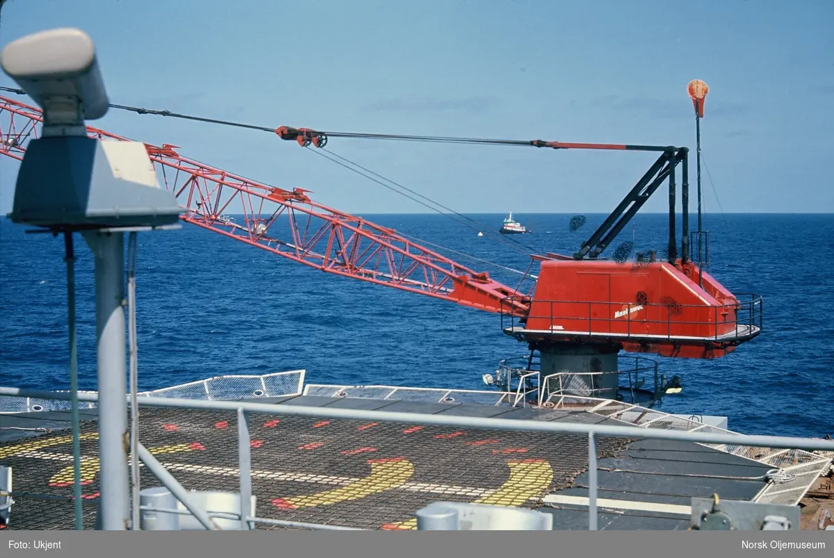 En liten heisekrane ved siden av en heliport offshore.