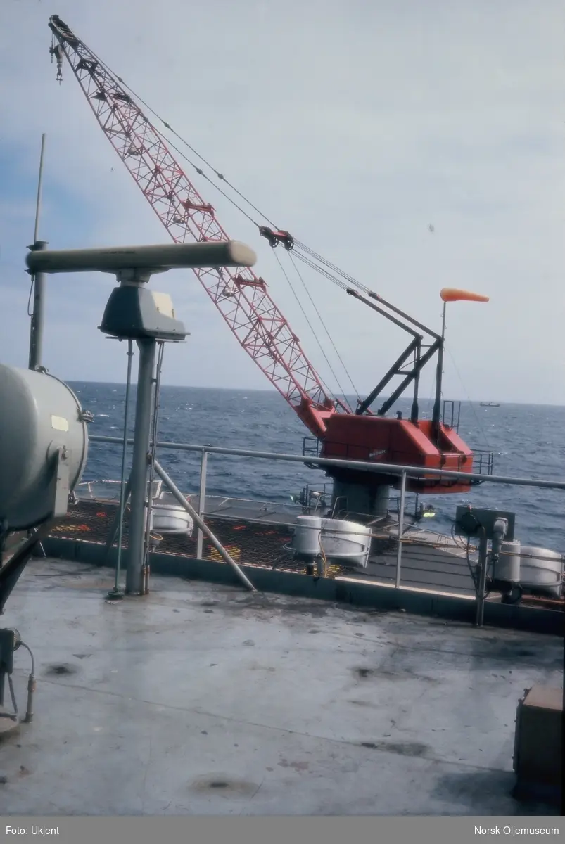 En liten heisekrane ved siden av en heliport offshore.
