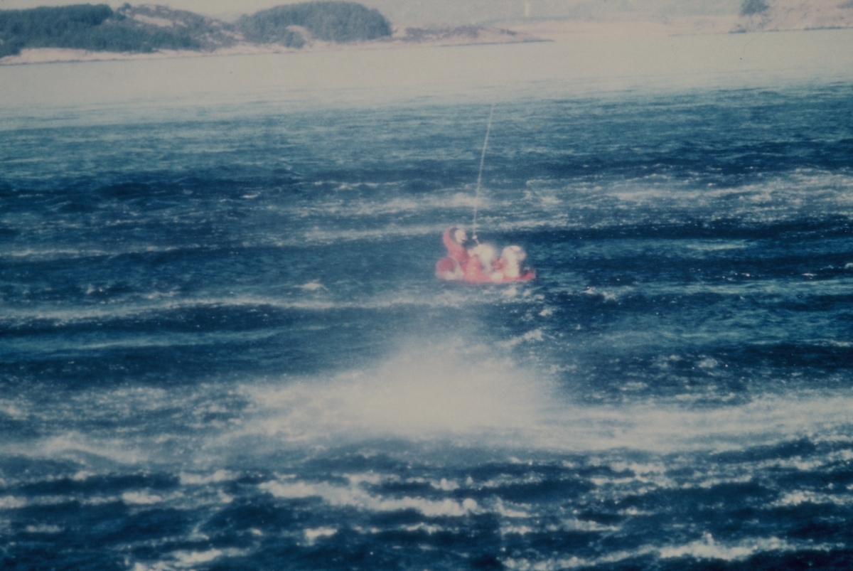 En livredder fires ned fra et helikopter til menn i overlevelsesdrakter i sjøen. På bilde 2 fester han et belte rundt mannen i sjøen og på det siste bildet heises de opp av sjøen.