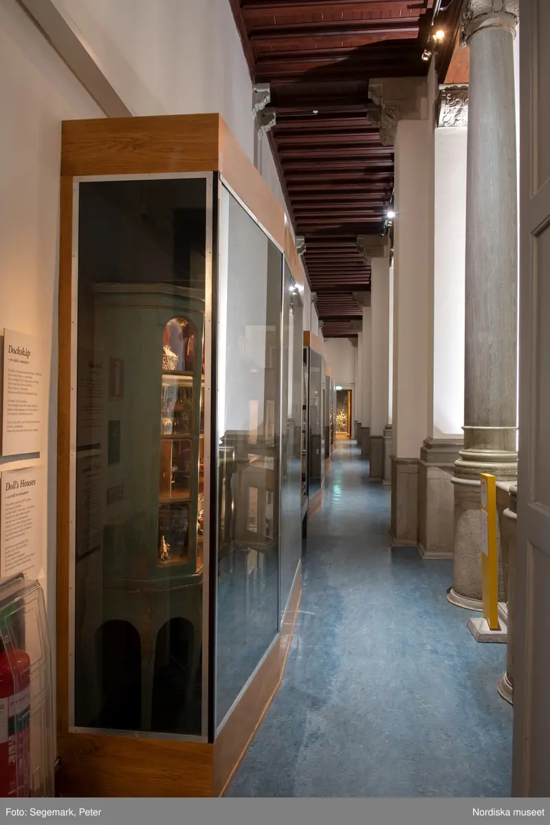 Dockskåp i utställningen "Dockskåp", visad på Nordiska museet 23 dec 1999 - 20 jan 2021.
Det blå kabinettskåpet, år 1760. Skåpet gjordes i ordning för Maria Catharina Falk som var en liten flicka vid mitten av 1700-talet. Det har ärvts och ändrats av andra. På väggarna hänger äkta porträtt av hennes och makens släkt.
I köket står en servis av fajans tillverkad 1746 vid Rörstrands porslinsfabrik. 
NM.0151825