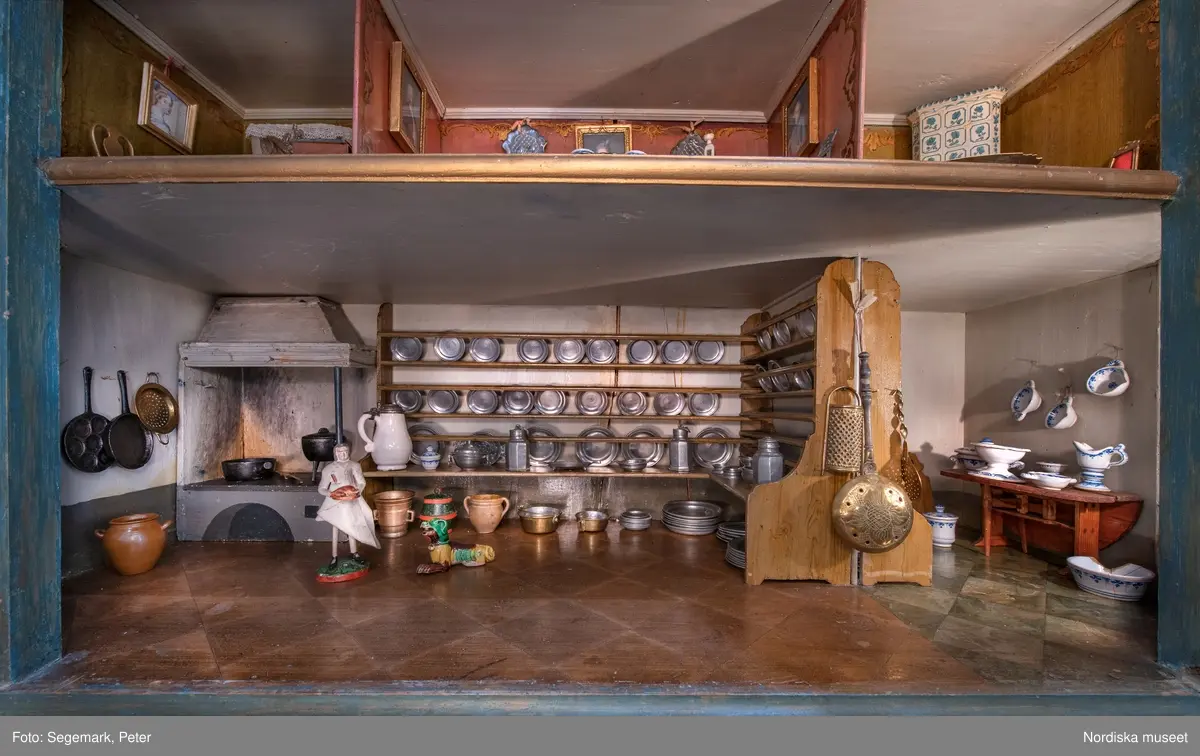 Dockskåp i utställningen "Dockskåp", visad på Nordiska museet 23 dec 1999 - 20 jan 2021.
Det blå kabinettskåpet, år 1760. Skåpet gjordes i ordning för Maria Catharina Falk som var en liten flicka vid mitten av 1700-talet. Det har ärvts och ändrats av andra. På väggarna hänger äkta porträtt av hennes och makens släkt.
I köket står en servis av fajans tillverkad 1746 vid Rörstrands porslinsfabrik. 
NM.0151825