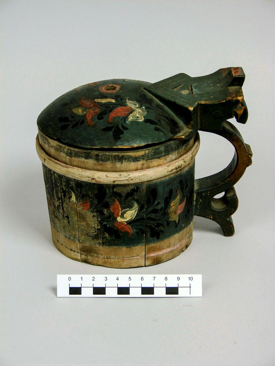 Dryckeskannor. A (brun): Dryckeskanna, av trä, laggad, med tre dubbelband. Konisk. Med lock. Gulfernissad. Locket med virvelstjärna i rött och grönt. Kring kannan nederst halvcirkelformiga, därovanför slingformiga och överst beslagsliknande ornament i rött, grönt och svart. Bottens undersida märkt m brännstämpel: M MS, inristat: IHD. Banden i rödbrunt. Diam(nedtill) 14,5 cm. H. 18,8 cm. Doroeta socken, Lappland. 
B Drickeskanna, av granträ, laggad. Ett band övriga bortfallna. Snidat trähandtag i svängda former. Propp överst i buktiga locket, bortfallen. Mörkgrön färg med blomdekor i rött, svart, vitt. Målningen delvis hårt sliten. Undertill ristat klumpigt BLD. Höjd 16 cm., diam. 13 cm. Inköpt av fru Johansson, Härnösand, april 1917, från Dorotea socken, Lappland. 
C (blå): Dryckeskanna av trä. Laggad, cylindrisk. Försedd med 4band placerade 2 och 2. Lodgrepe, överst med tumgrepp samt gångjärn till locket. Grepen har eventuellt haft 2 grepp varav det yttre(?) är avbrutet. Locket är cylindriskt med konvex ut- och konkav insida. Framtill är en liten spets utdragen. Bottnen är fäst i fasat spår i stavarnas nederdel. Blåmålad med stiliserade blommor i beige, gult och rött på svarta kvistar. Banden och lockets kant är röda. Brännstämpel på undersidan: Ett konstigt E med prickar över. 