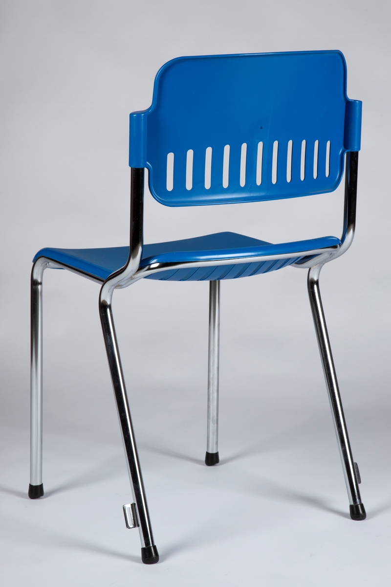 Stol med ramme i forkrommet metall og med åpen rygg. Sete og rygg i støpt, blå plast (polypropylen). Stolen er enkelt ergonomisk formet med 12 gjennombrutte rifler innerst på setet og nederst på ryggen. Stolen kan stables og har feste på hver side av bakbena for side-hekting av stoler i rekke.