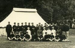 Gruppebilde,soldater,sykepleier foran telt.Ukjent. Postkort.